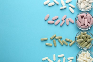 Photo of Different vitamin pills on light blue background, flat lay. Space for text