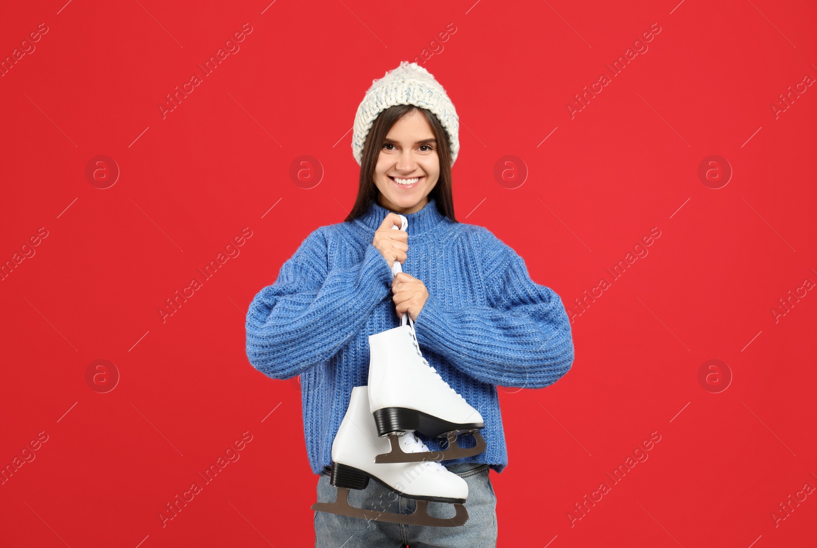 Photo of Happy woman with ice skates on red background