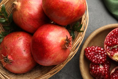 Photo of Fresh pomegranates and green leaves on grey table, top view