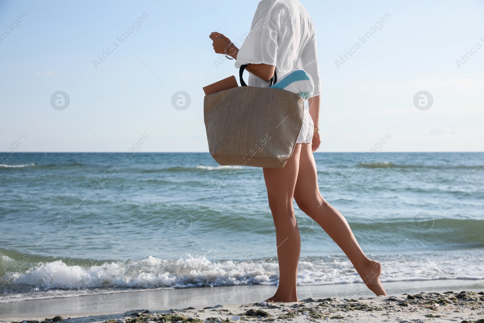Photo of Woman carrying bag with beach towel near sea, closeup