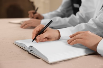 Photo of People writing notes in notebooks at table during lecture, closeup. Professional butler courses