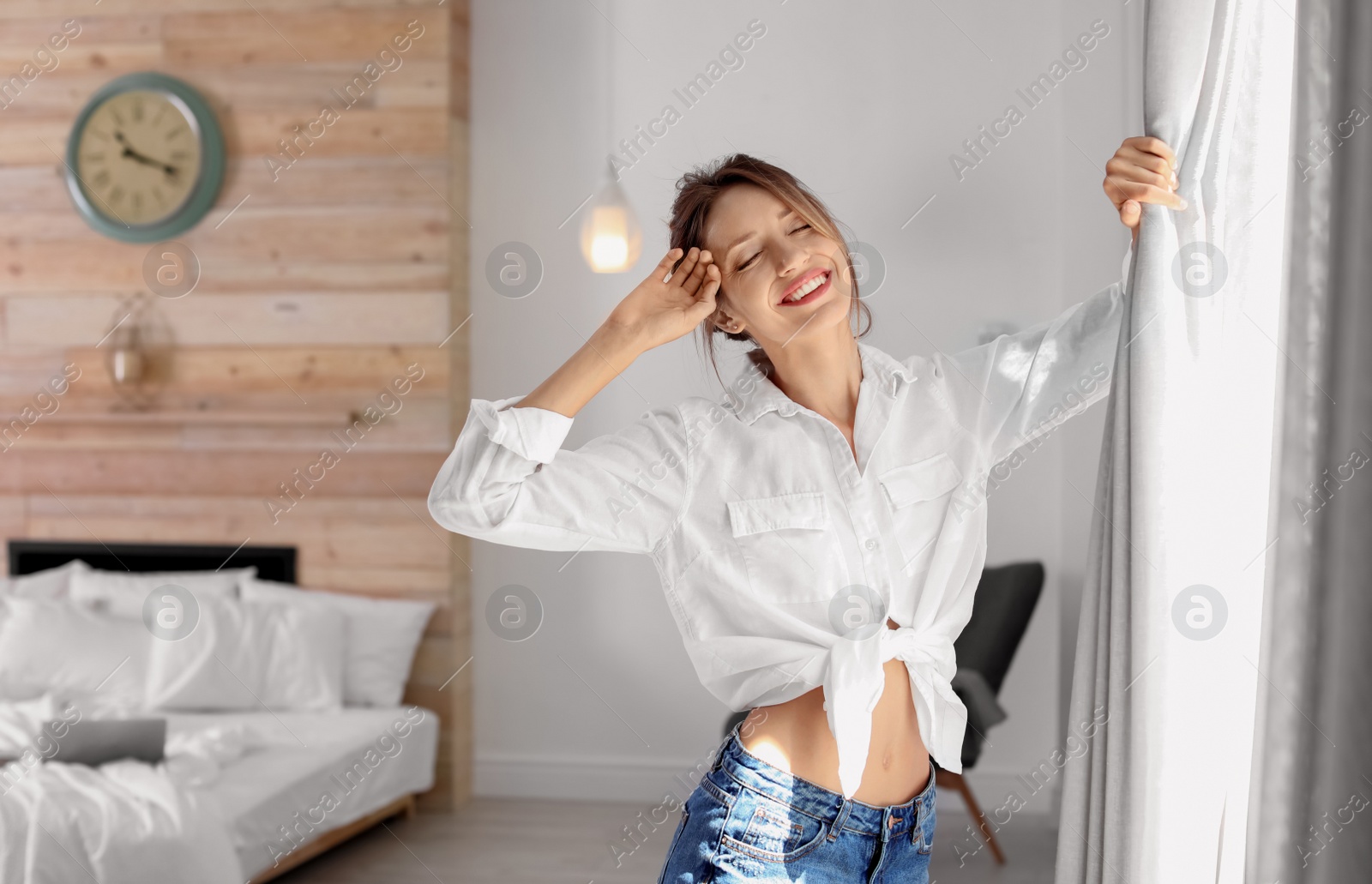 Photo of Young happy woman near window at home. Lazy morning