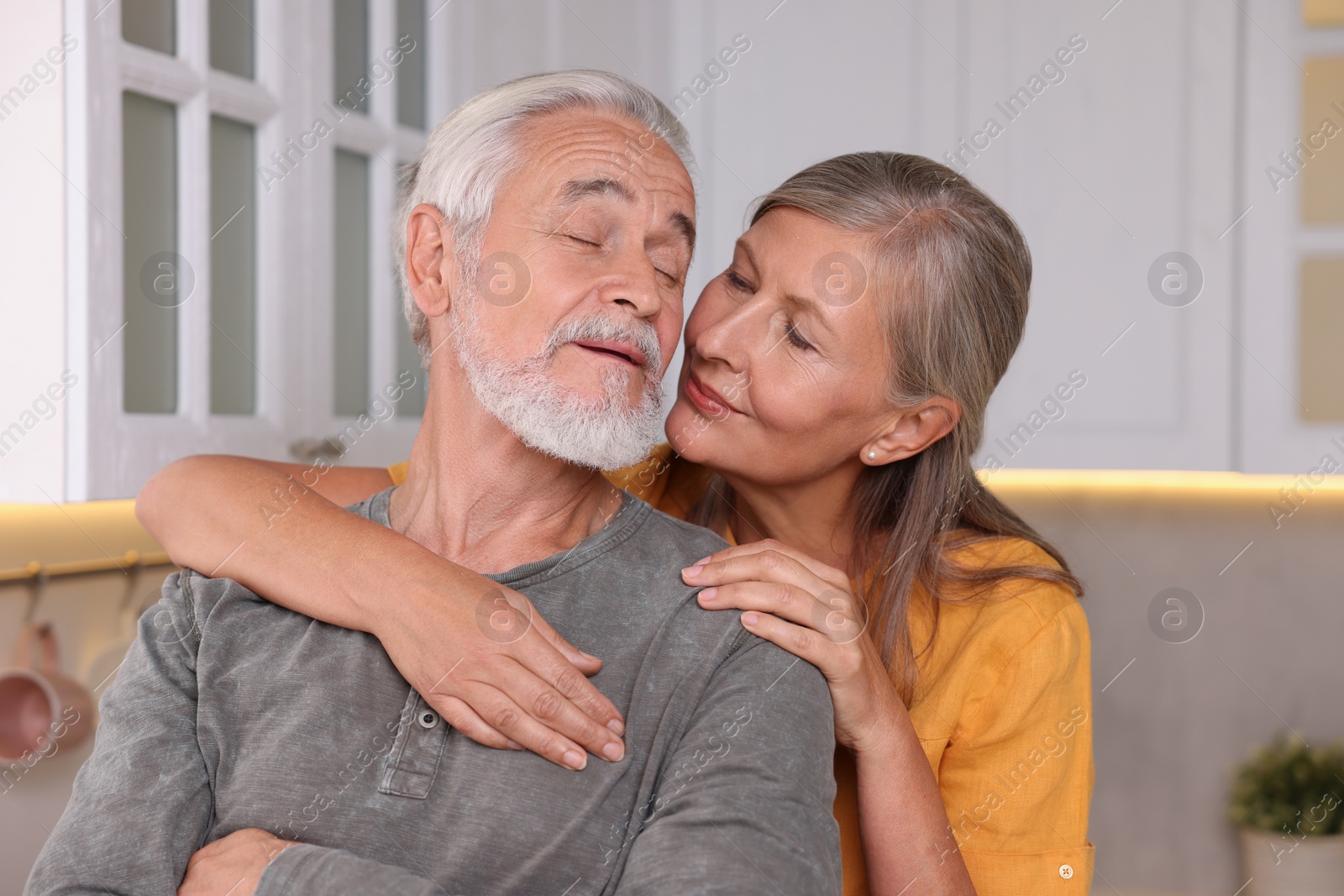 Photo of Senior woman kissing her beloved man in kitchen