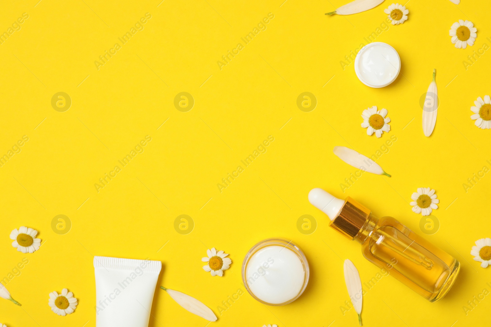 Photo of Flat lay composition with chamomiles and cosmetic products on yellow background. Space for text