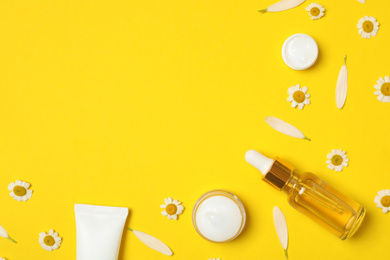 Photo of Flat lay composition with chamomiles and cosmetic products on yellow background. Space for text