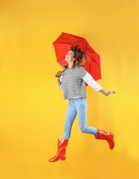 Woman with red umbrella near color wall