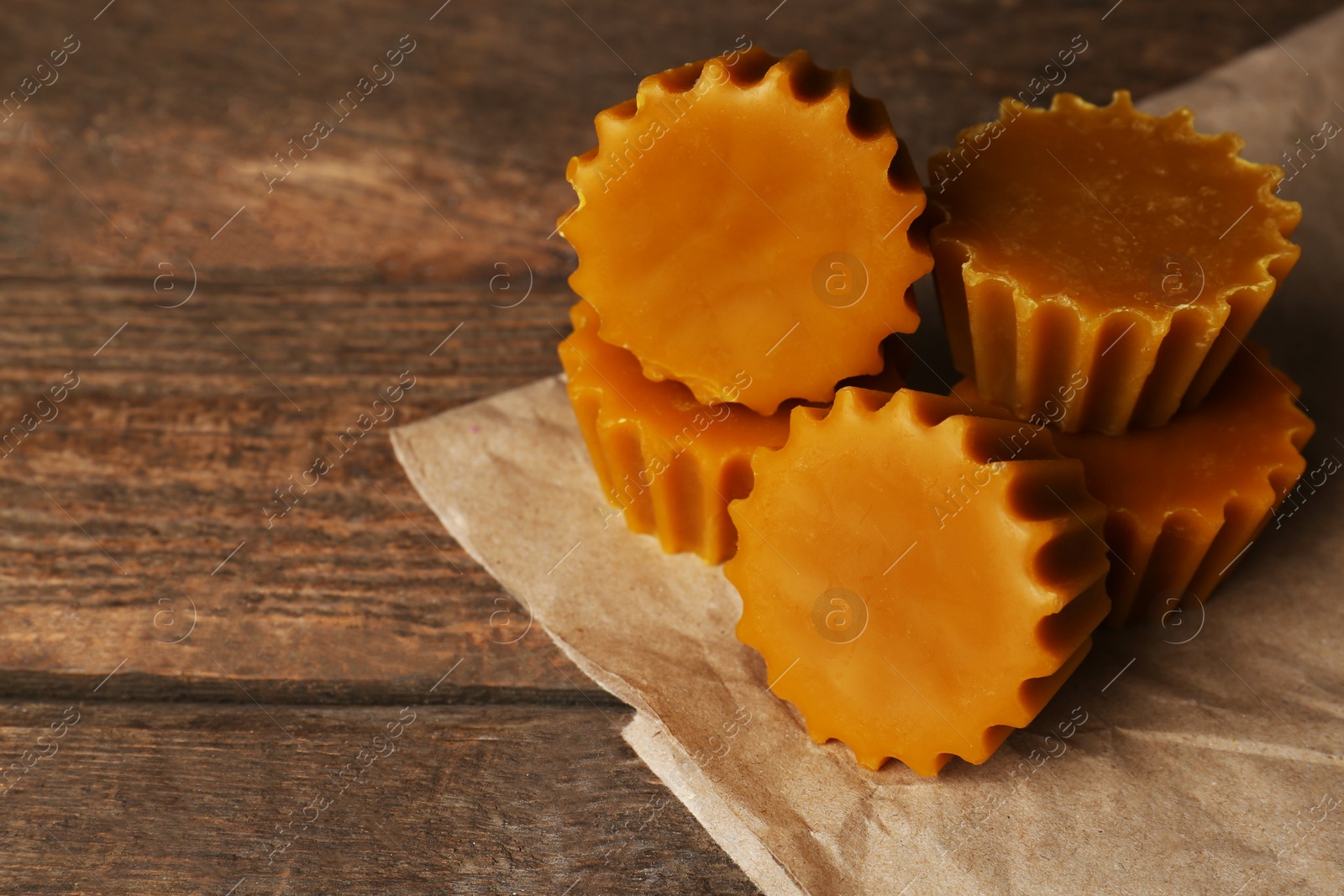 Photo of Natural beeswax cake blocks on wooden table, closeup. Space for text