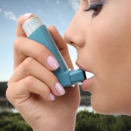 Image of Woman using asthma inhaler, closeup. Emergency first aid during outdoor recreation