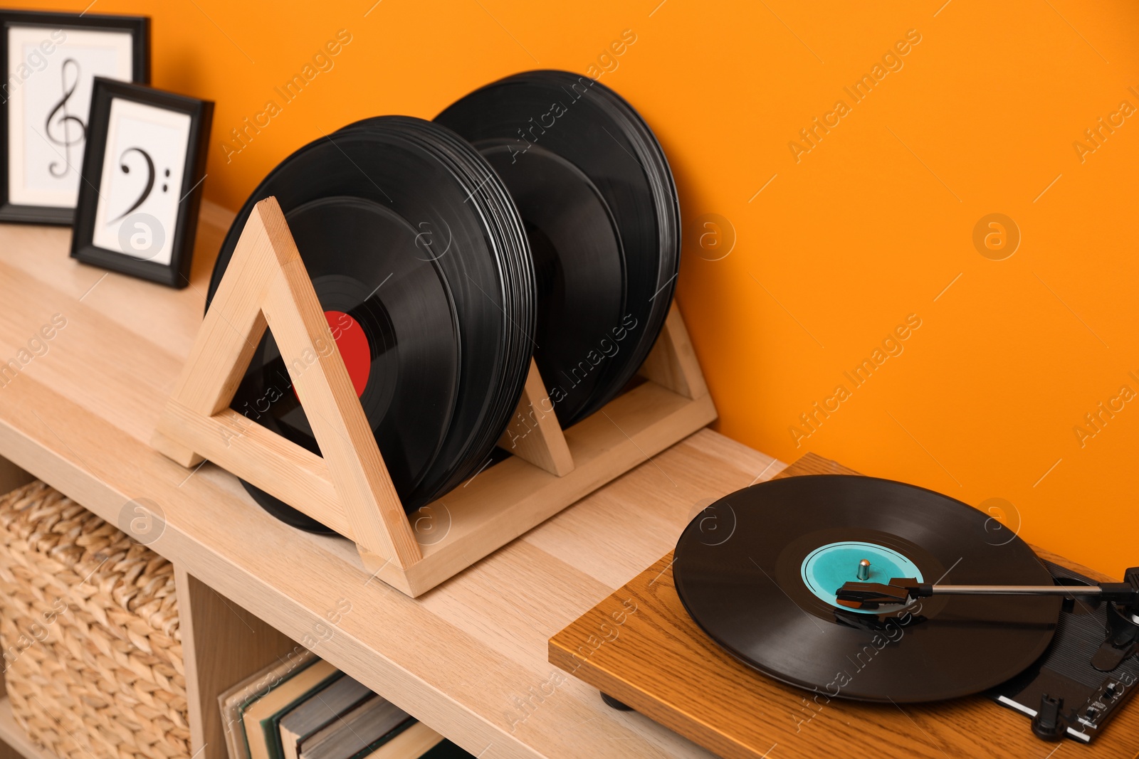 Photo of Vinyl records and player on wooden cabinet near orange wall