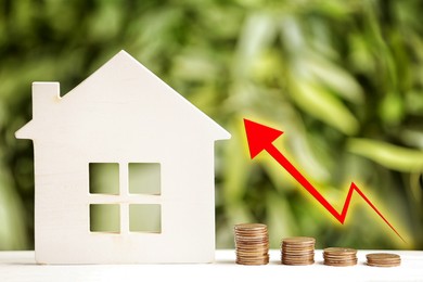 Image of Mortgage concept. House model and coins on white table against blurred green background 