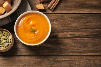 Flat lay composition with bowl of tasty sweet potato soup and space for text on wooden background