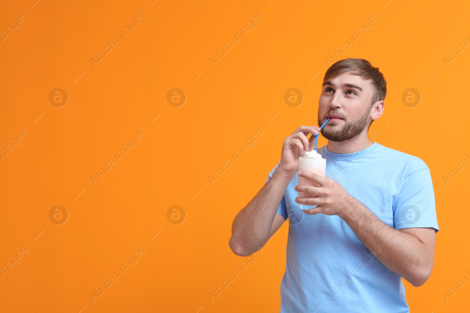 Photo of Young man with glass of delicious milk shake on color background