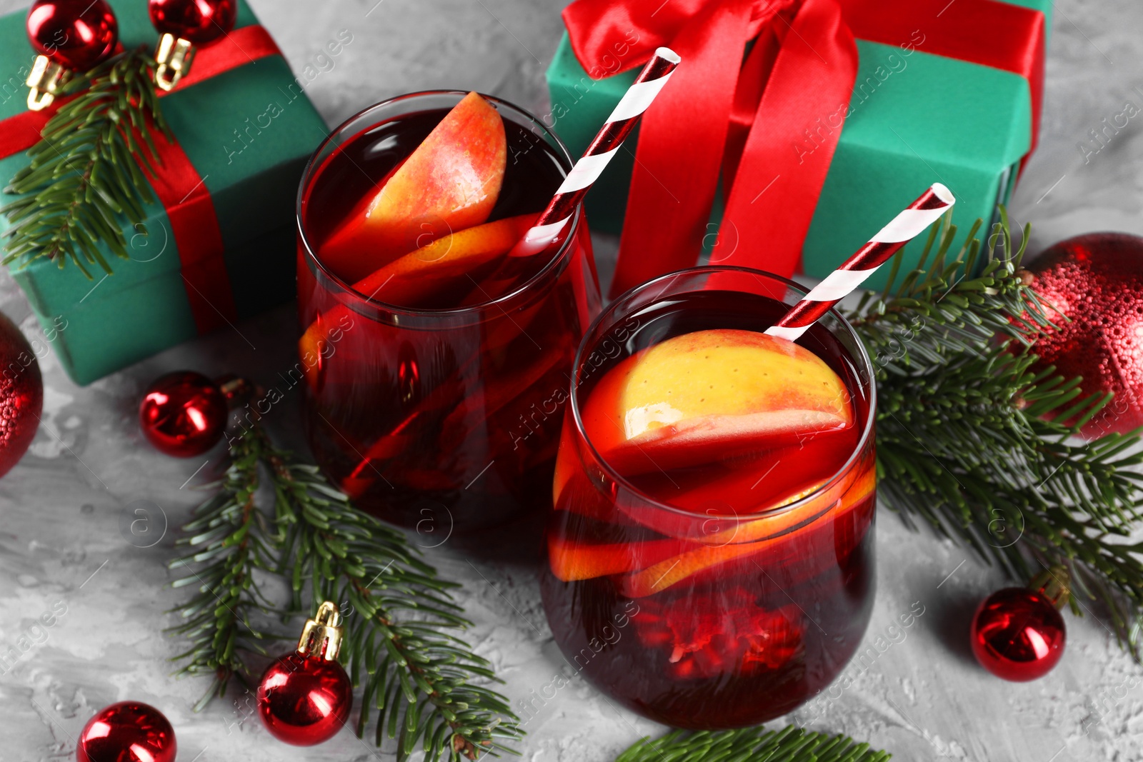Photo of Delicious Sangria drink in glasses and Christmas decorations on grey textured table, above view