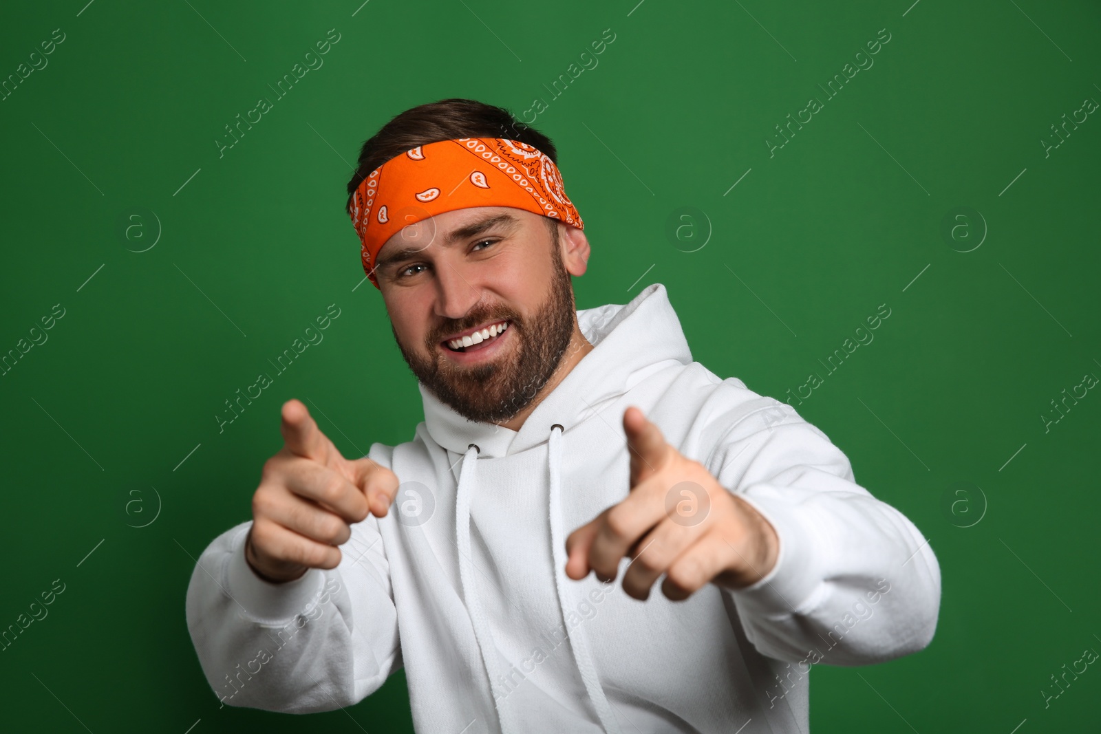 Photo of Fashionable young man in stylish outfit with bandana on green background