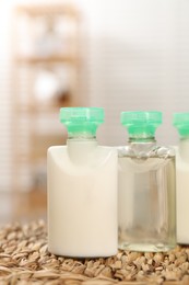 Photo of Mini bottles of cosmetic products on wicker mat against blurred background, closeup