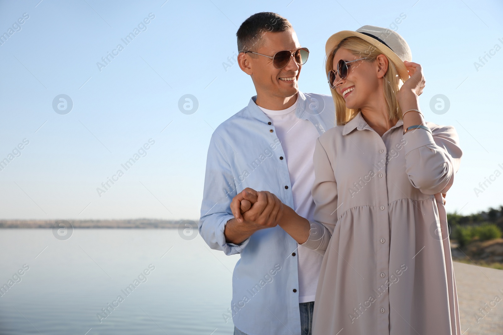 Photo of Happy couple walking along waterfront on summer day