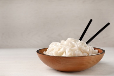 Photo of Bowl with rice noodles on table. Space for text