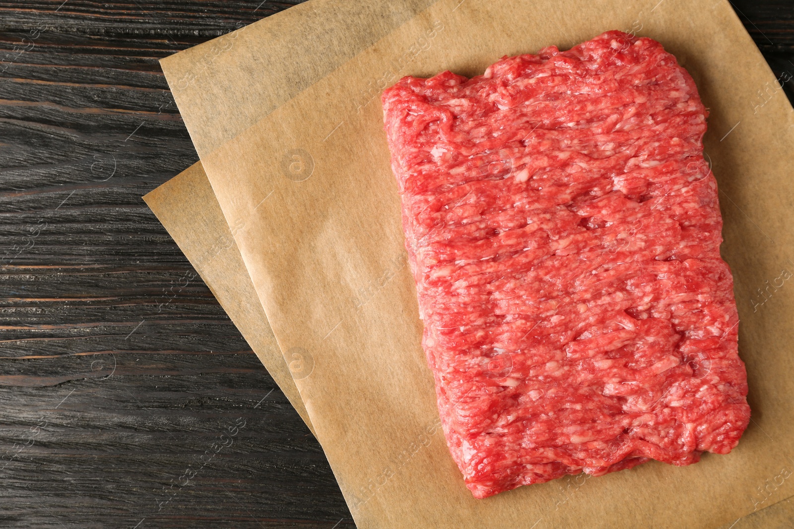 Photo of Fresh raw minced meat on black wooden table, top view