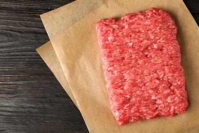 Photo of Fresh raw minced meat on black wooden table, top view