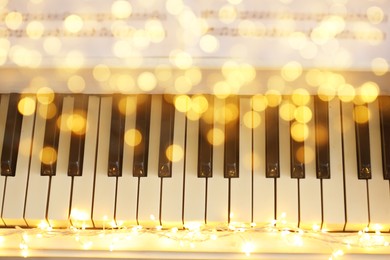 Image of Christmas and New Year music. Piano with fairy lights, bokeh effect