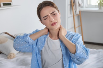 Photo of Woman suffering from neck pain in bedroom