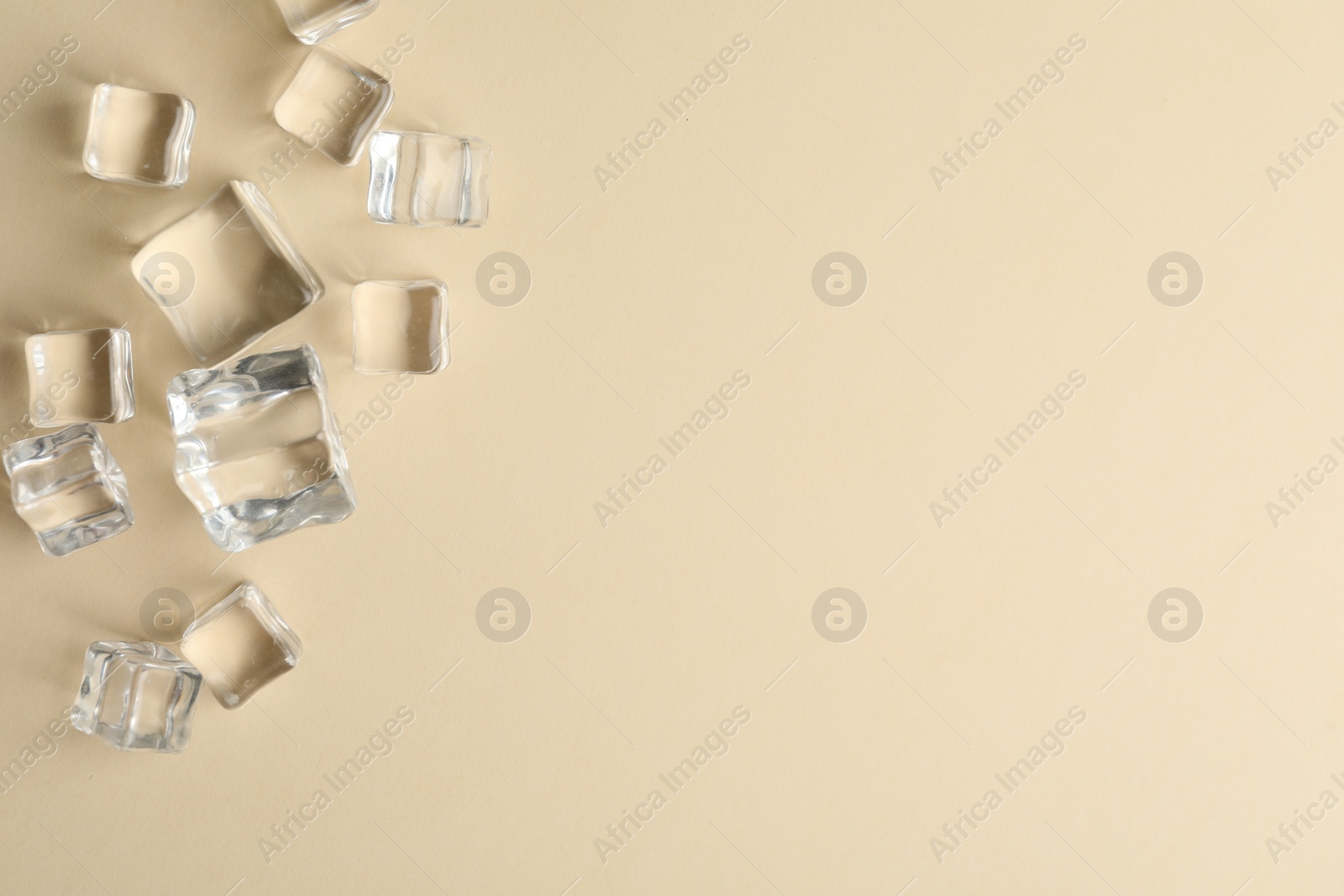 Photo of Crystal clear ice cubes on beige background, flat lay. Space for text