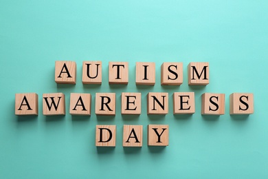 Photo of Cubes with phrase "Autism awareness day" on color background