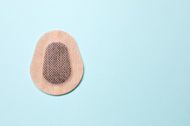 Contraceptive patch on light blue background, top view. Space for text