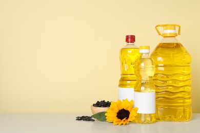 Photo of Bottles of cooking oil, sunflower and seeds on white table, space for text
