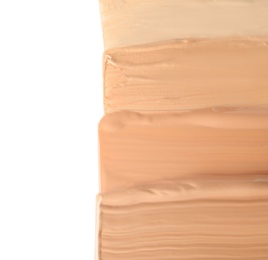 Photo of Samples of different foundation shades on white background, top view