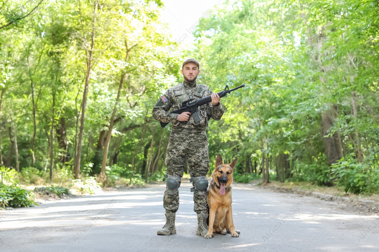 Photo of Man in military uniform with German shepherd dog outdoors