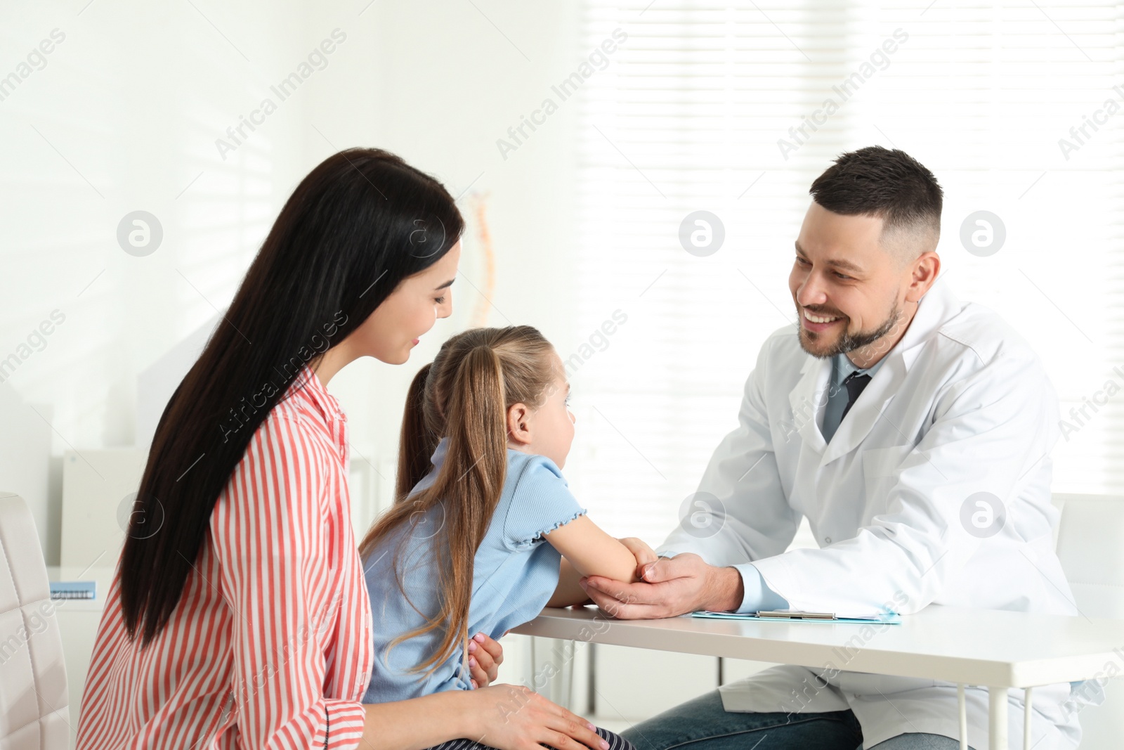 Photo of Little girl with mother visiting orthopedist at clinic