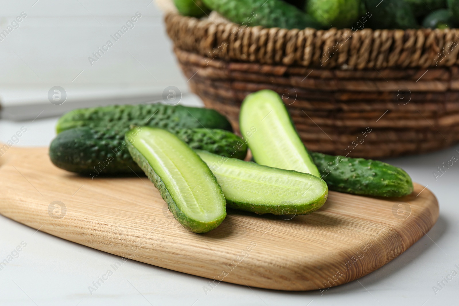 Photo of Whole and cut fresh ripe cucumbers on white table