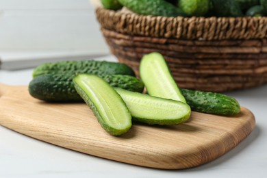 Photo of Whole and cut fresh ripe cucumbers on white table