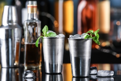 Metal glasses with delicious mint julep cocktail on bar counter