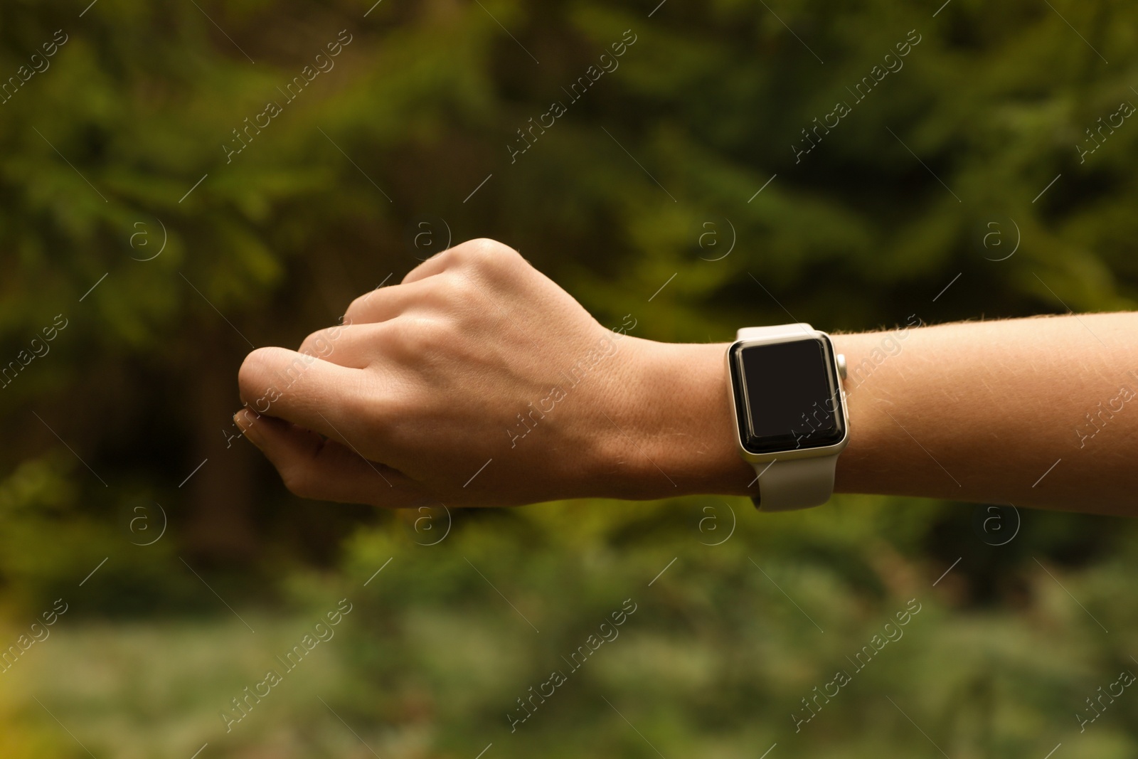 Photo of Woman checking smart watch with blank screen in wilderness, closeup