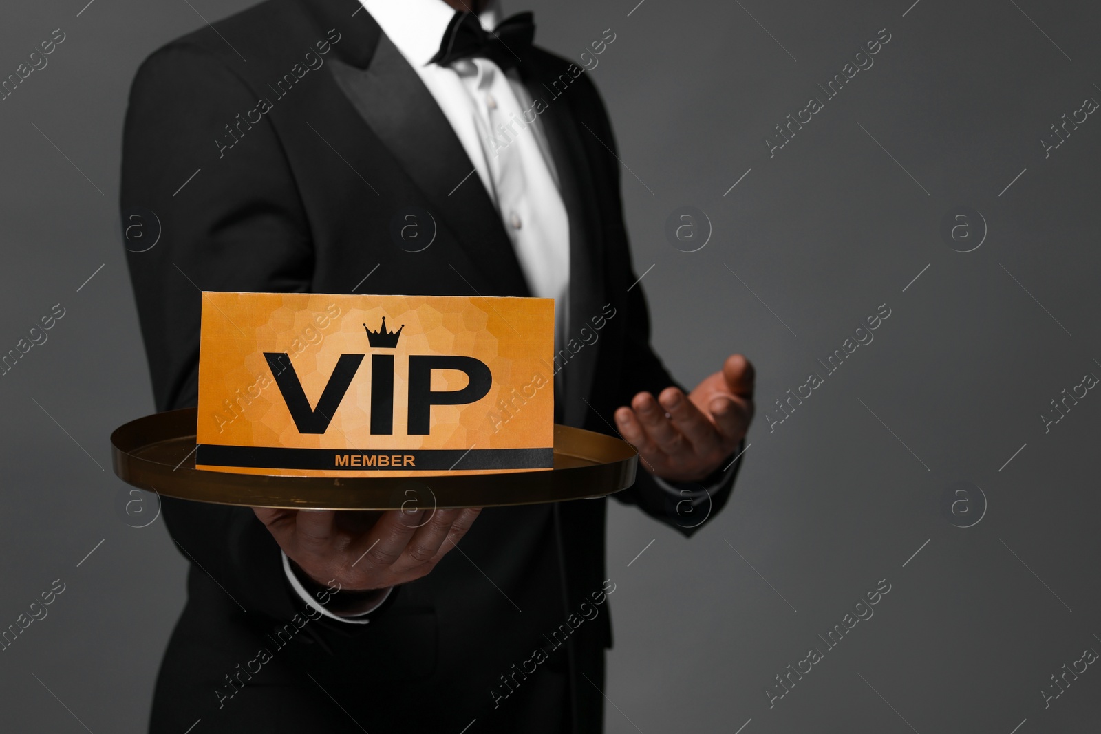 Photo of Man holding tray with VIP sign on grey background, closeup. Space for text