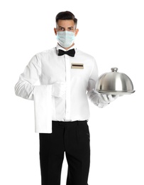 Photo of Waiter in medical face mask holding tray with lid on white background