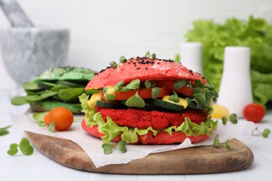 Photo of Tasty pink vegan burger with vegetables, patty and microgreens on white tiled table, closeup