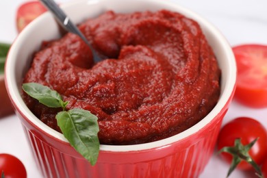 Photo of Tasty tomato paste and basil in bowl, closeup