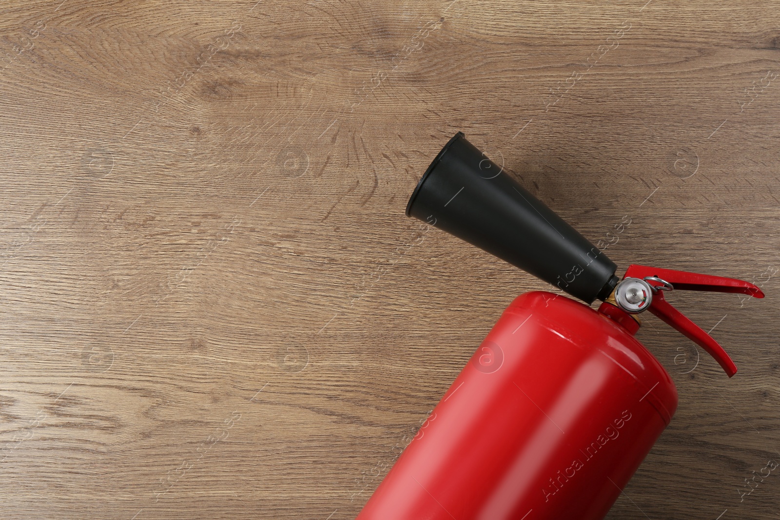 Photo of Fire extinguisher on wooden background, top view. Space for text