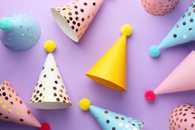 Beautiful party hats on purple background, top view