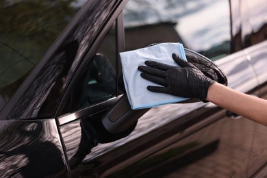 Woman wiping her modern car with rag, closeup