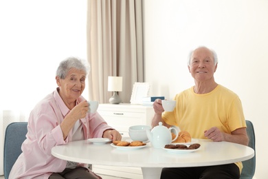 Elderly people having breakfast at nursing home. Assisting senior people