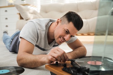 Happy man using turntable while lying on floor at home