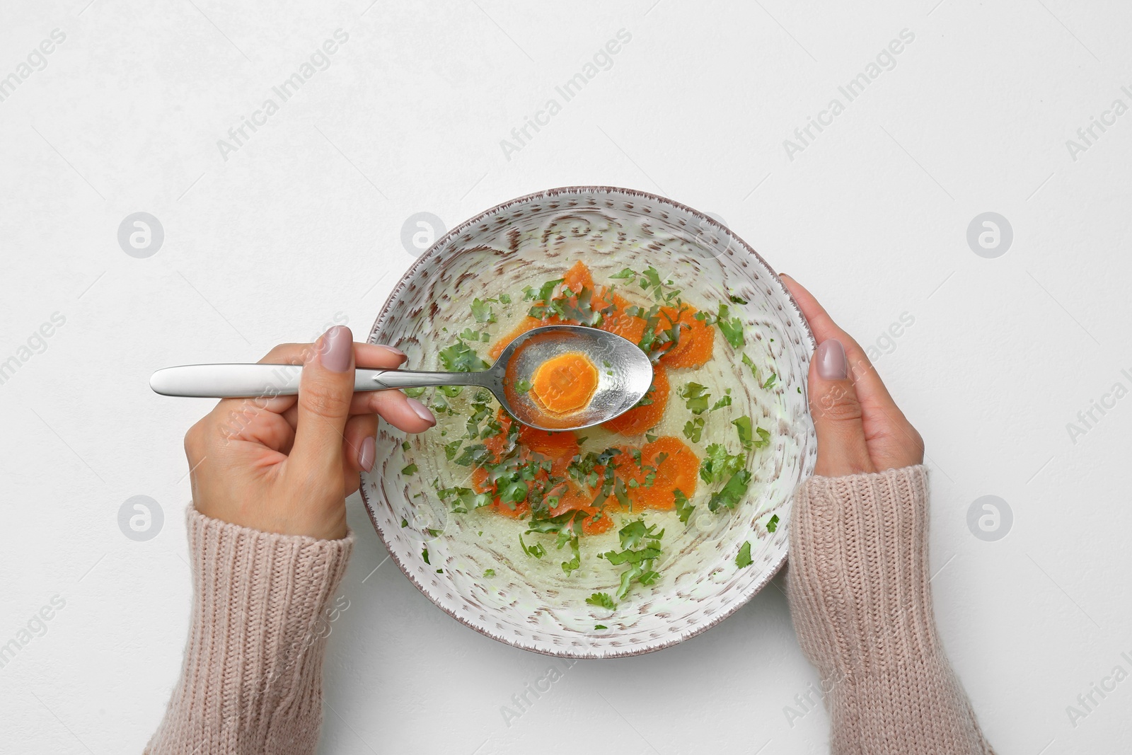 Photo of Woman with bowl of soup at white table, top view. Flu treatment