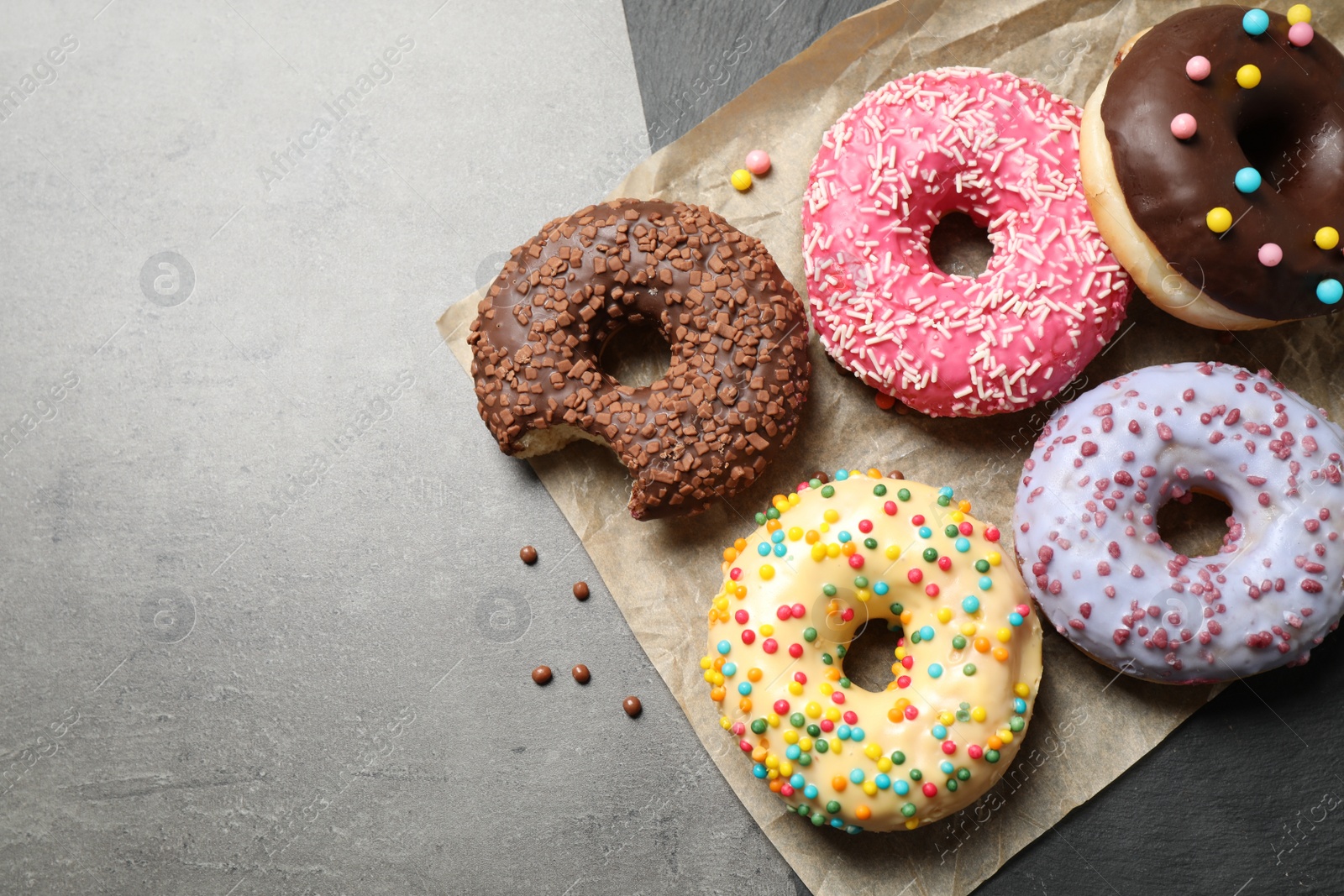 Photo of Delicious glazed donuts on grey table, top view. Space for text