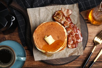 Photo of Delicious pancakes with maple syrup, butter and fried bacon on wooden table, flat lay