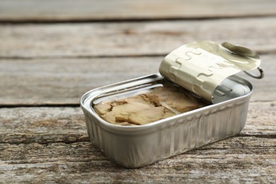 Open tin can of tasty cod liver on wooden table, closeup