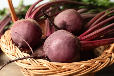 Photo of Raw ripe beets in wicker basket, closeup